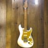 MS-1-Artisan-WB- White solid-body electric guitar with a gold pickguard resting on a wooden floor.